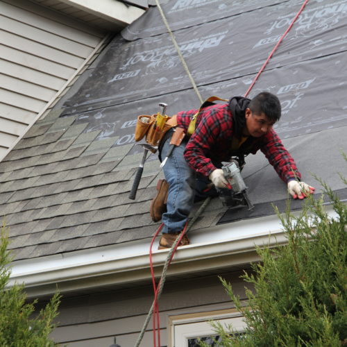 Roofing technician using an automatic roofing nail gun